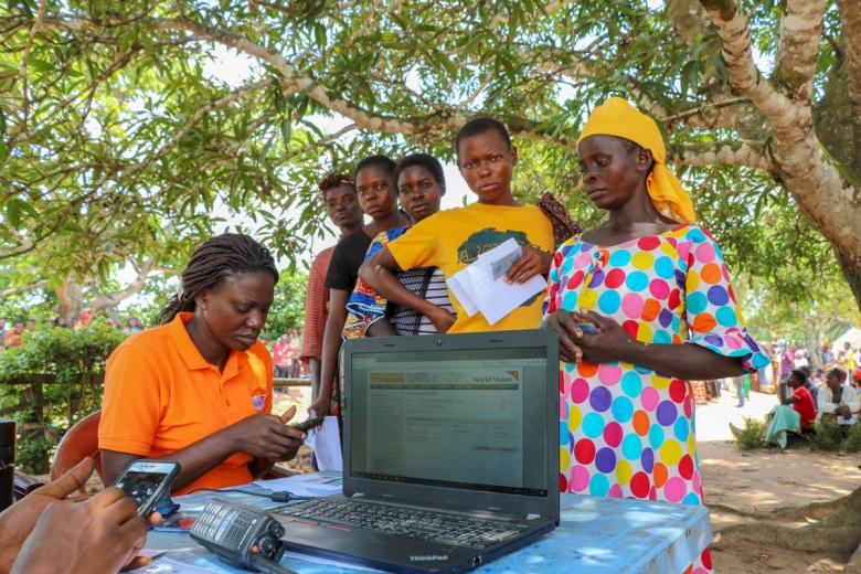 Member of the cash team in DRC verify people’s identities against their registration details and photos, as part of a World Vision cash assistance project. Kate Shaw/World Vision