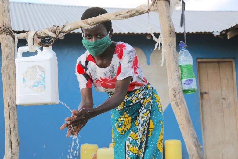 A masked girl washing her hands
