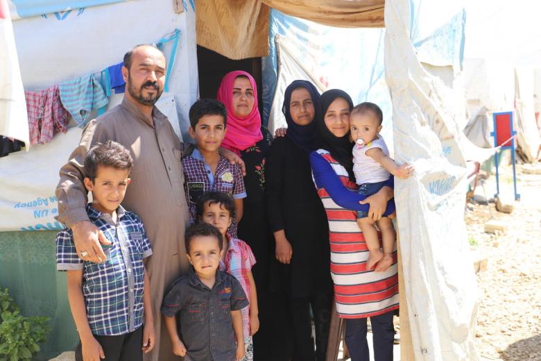 A Syrian family outside their refugee shelter
