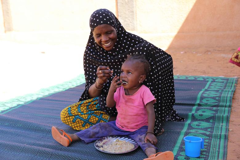 Bassira feeding her daughter Fadjimata