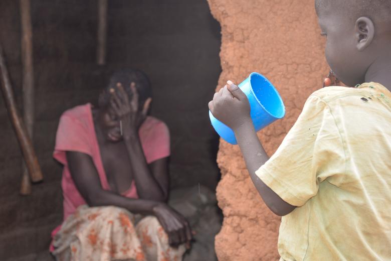 Magdalena looking on as her grandchild eats porridge