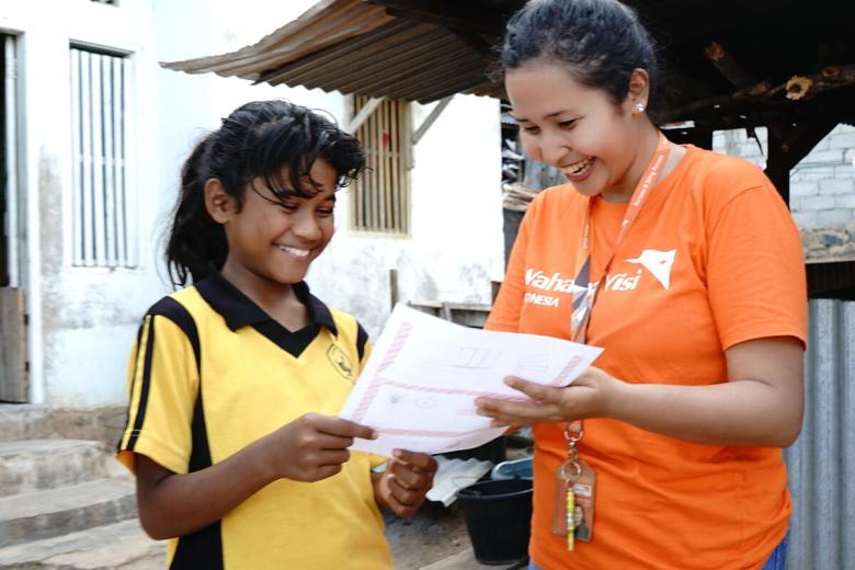World Vision staff reads a letter from a sponsor with sponsored child