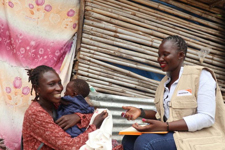 World Vision staff speaks with monther of young child in Africa