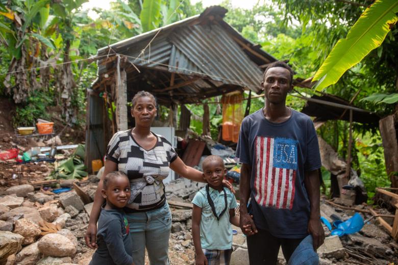 Family that lost their home in Haiti earthquake stands in front of the rubble