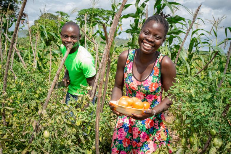 Child in Africa holds produce that her family grew thanks to support from sponsors