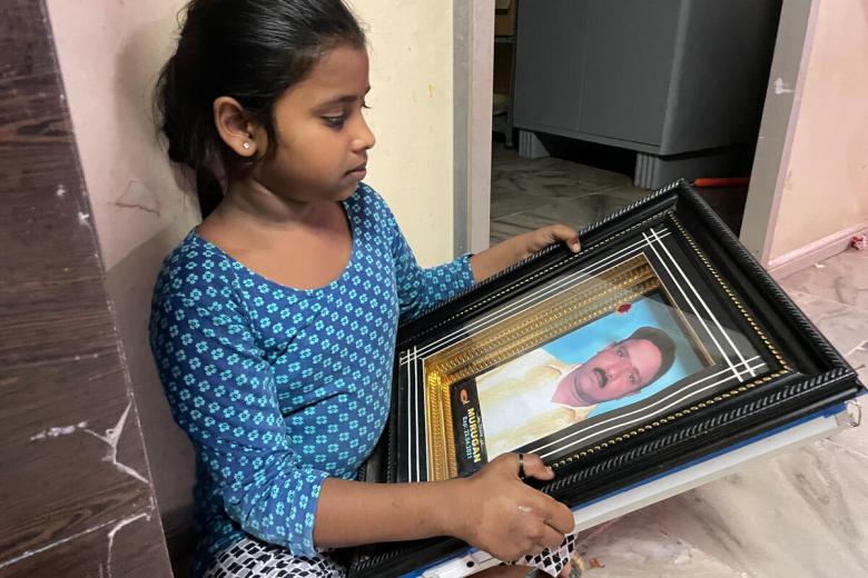 9-year-old Ashmitha looks at a picture of her father. This will be her first Christmas without him