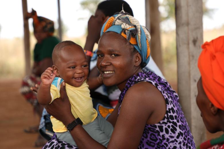 A woman jovially smiles with her child when they attended clinic at Iglansoni health center in Singida region