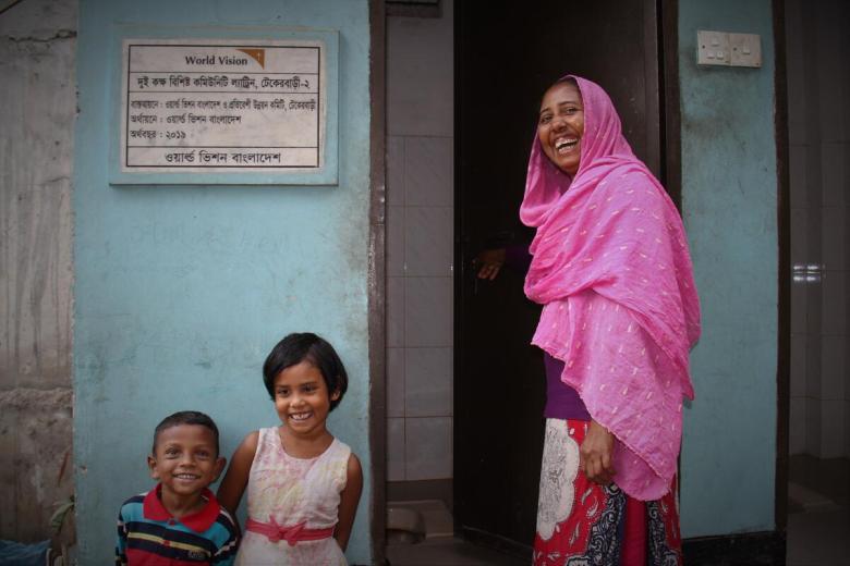 Woman outside a clean toilet built in Bangladesh
