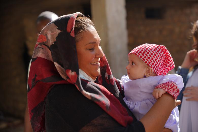 World Vision Iraq Response Director Nicole Peter meeting a newly baptised Yazidi child in her purple dress and her special red and white checked head-scarf. Photo: Shwan Mohamed Amin