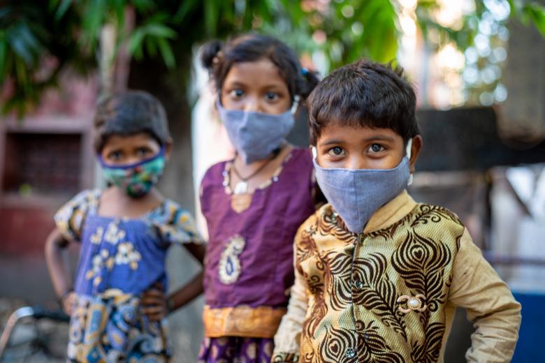 Three children in India wearing masks looking at the camera