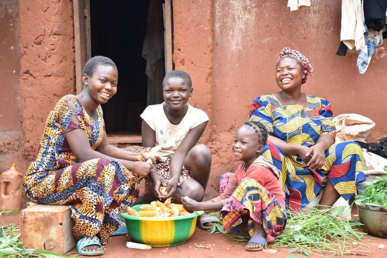sponsored children with their mother sit outside their home in the DRC