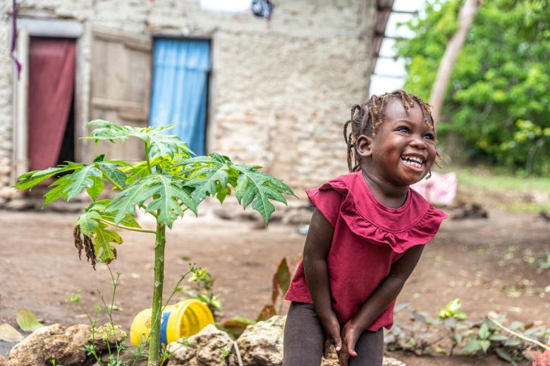 Sponsored child in Haiti grows health and strong and enjoys helping her mother grow papaya and other fruits