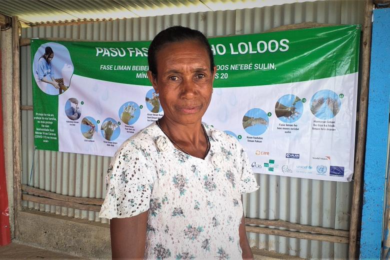 Amelia is standing in front of prevention awareness banner after meeting World Vision. Image: Natalino Tilman / World Vision