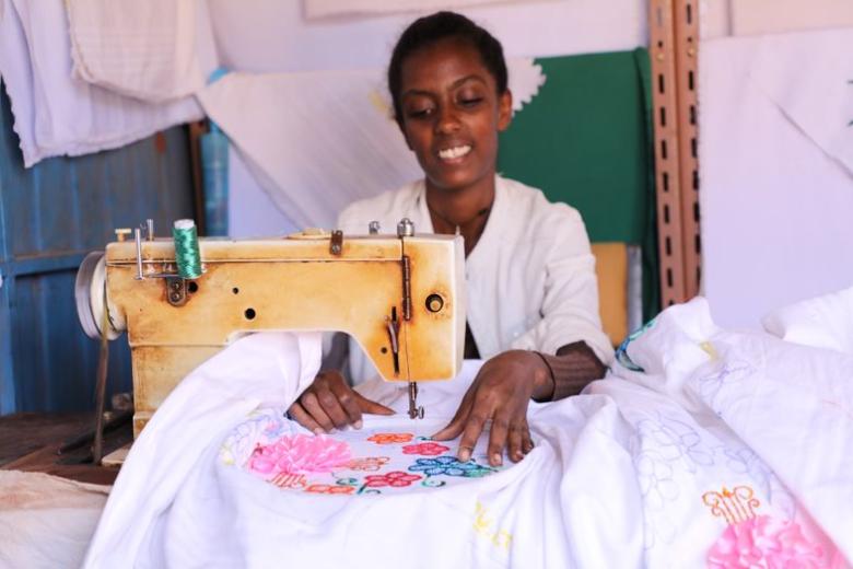 Woineshet Bekele smiling sitting on a sewing machine