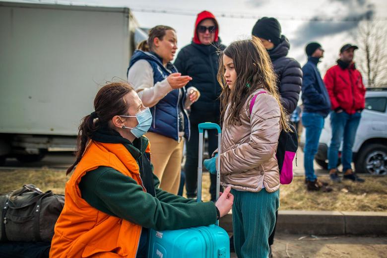 World Visions staff speak with a young girl on the Romania border