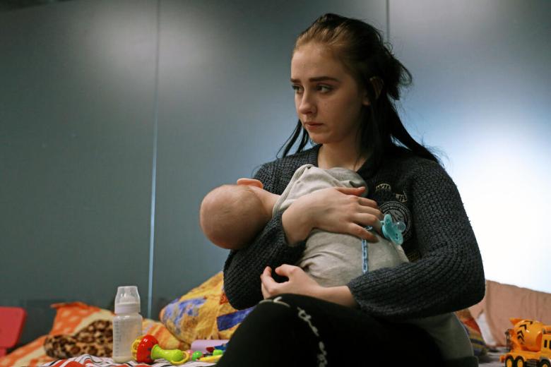 Lisa and her baby seated on a bed