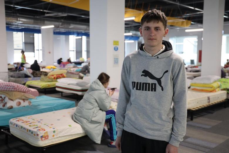 Oleksandr stands in a refugee center