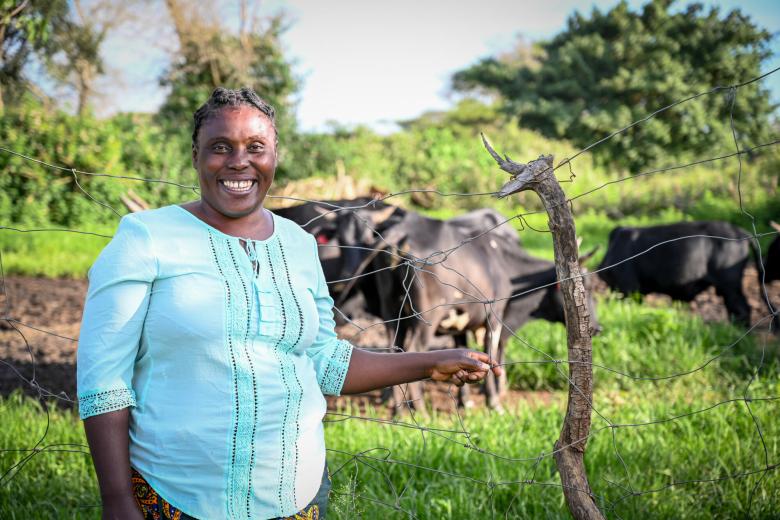 Agatha M with her cattle that she bought with World Vision help