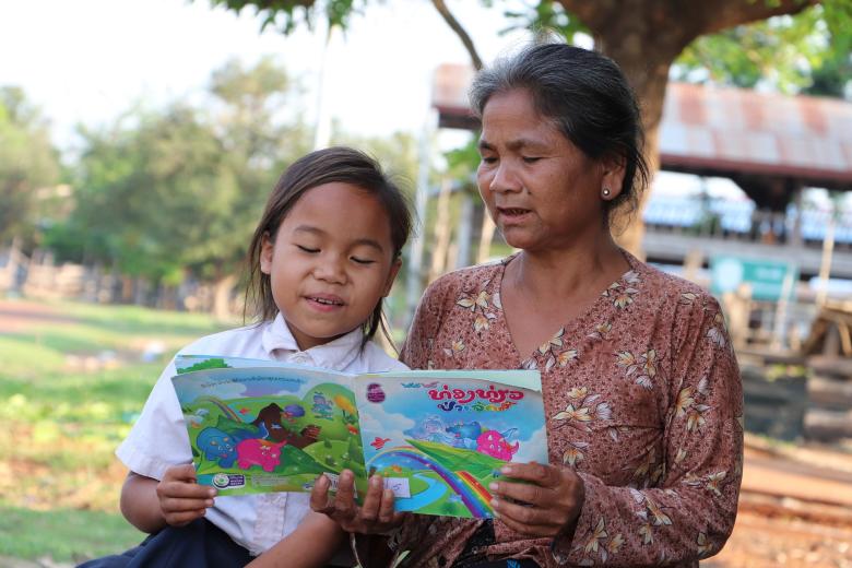 Kam and her grandmother as she reads her storybook.