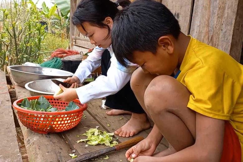children prepare food on the floor outside their house