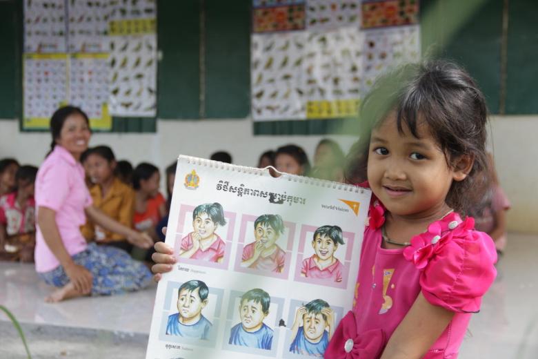 child holds up educational material