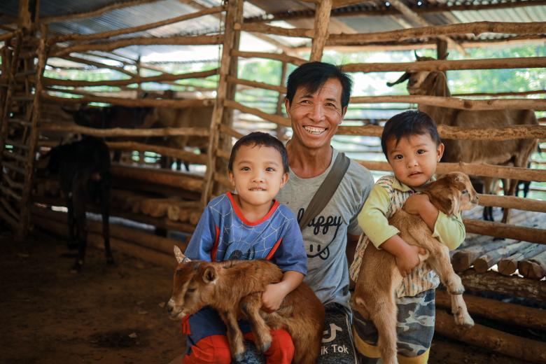 Ngwar Tar enjoys seeing his grandchildren smile while playing with the baby goats in his small goat farm