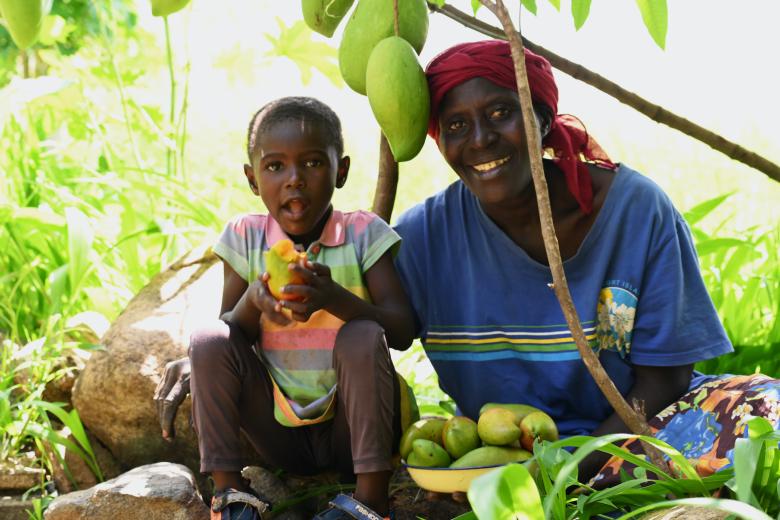 Joyce and her granddaughter Blessing under a mango tree at the family farm in Emsea village, Elgeyo Marakwet County. ©World Vision Photo/ Hellen Owuor