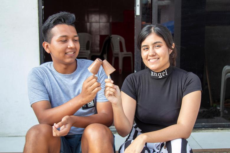 Two young people on a step in Ecuador eating ice cream