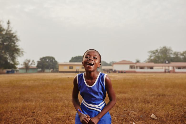 young girl stands in a field smiling and laughing
