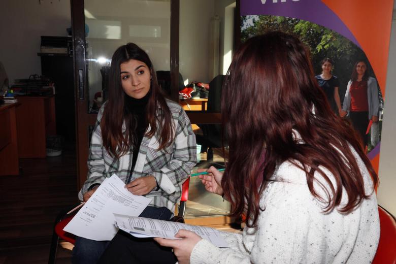 Andreea sits and talks with another volunteer