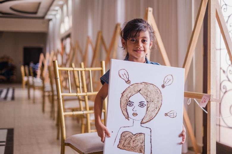 Girl proudly shows off her artwork at the workshop.