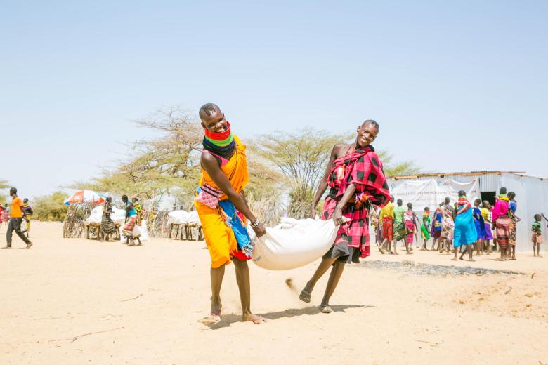 Beneficiaries carry food at a food distribution in Kenya