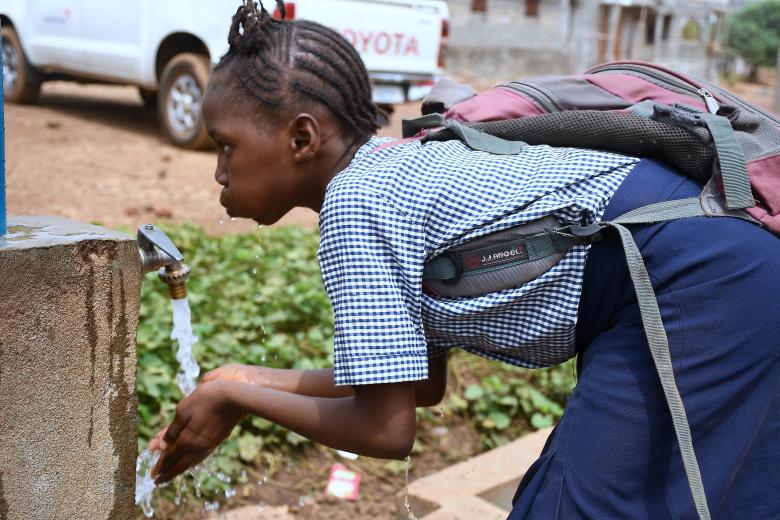 A school pupil enjoying water from one of the World Vision installed taps in her school compound