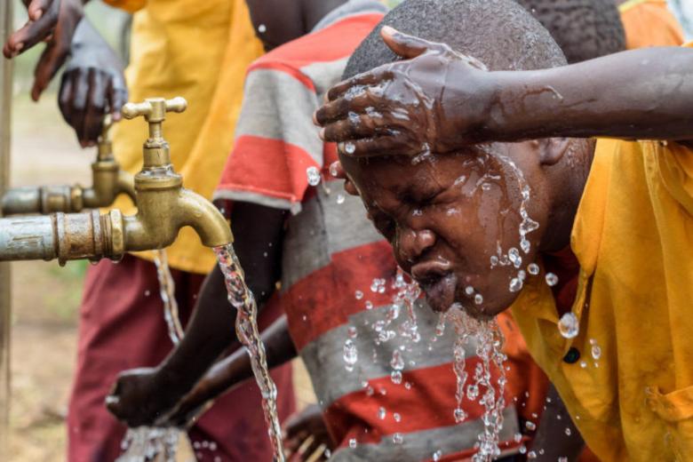 Child washing face from piped water