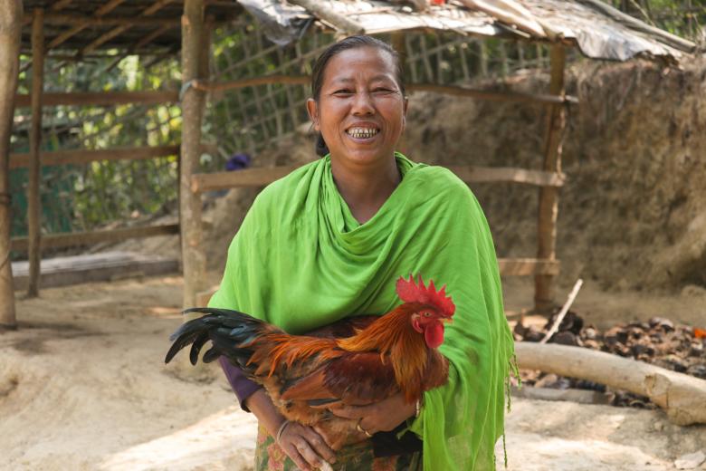 One figure, a woman holding a chicken and smiling
