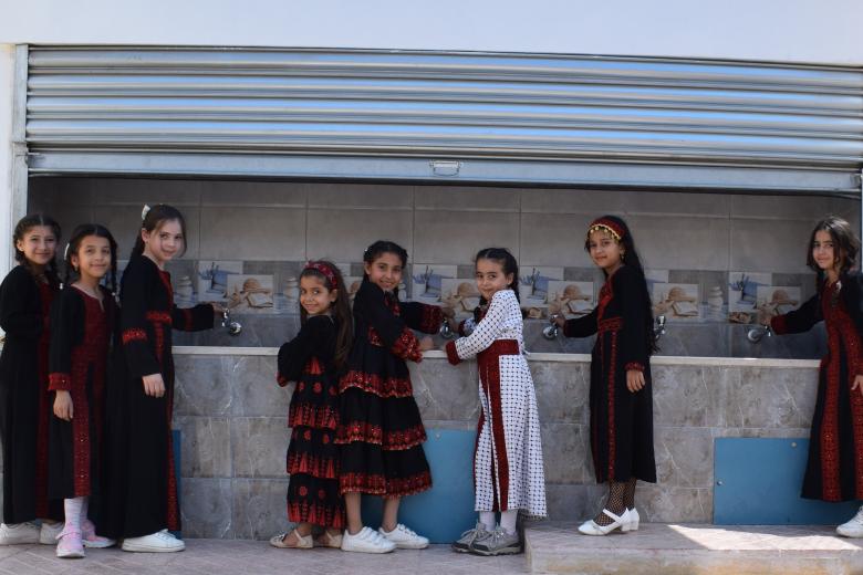 Group of Palestinian students around the new water taps