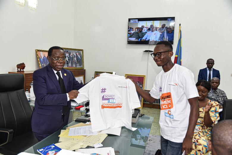 Un enfant remettant un t-shirt au président du sénat en guise de son enrôlement comme acteur de changement