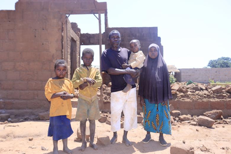 Marcelino and his children standing in front of the destroyed house