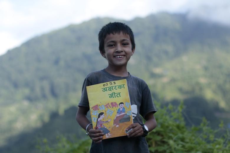 Child holds mother language book