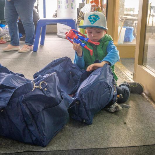 Refugee child from Ukraine sits by their family's bags