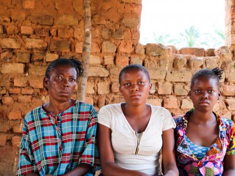 Maria sits with her daughters Joelle and Jeanette in a village in Dibaya territory. The girls walked for three months to get to Kasai Central from Tshikapa, where they grew up.