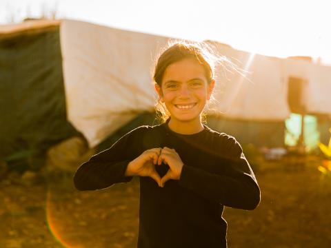 Syrian girl making a hear with her hands at sunset