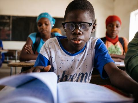 Boubacar reads his textbook during school