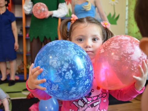 A young Georgian girl holds balloons in her classroom