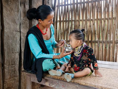 Mana feeds her child nutritious food in Nepal