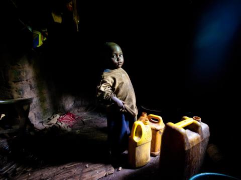 A young Burundi child stands in his home