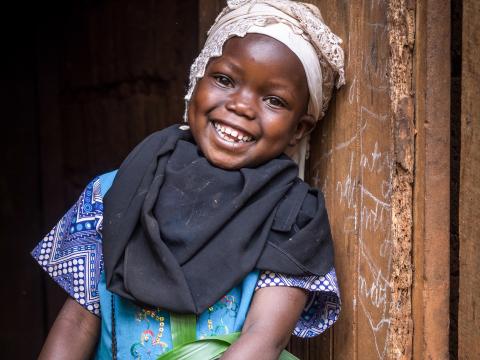 A girl stands against a wall smiling