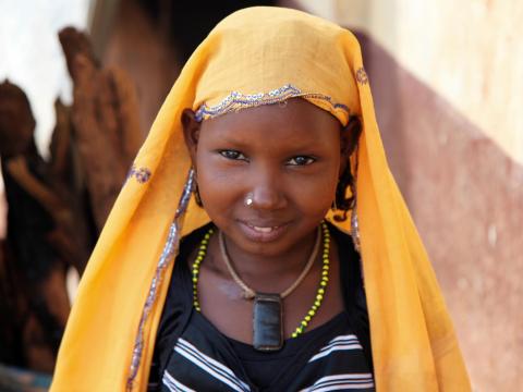 A girl in the Central African Republic stands with a yellow scarf on her head