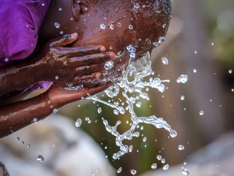 A young girl washes her face with clean water