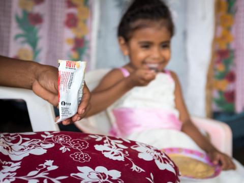 A girl in Latin America eats a food pouch